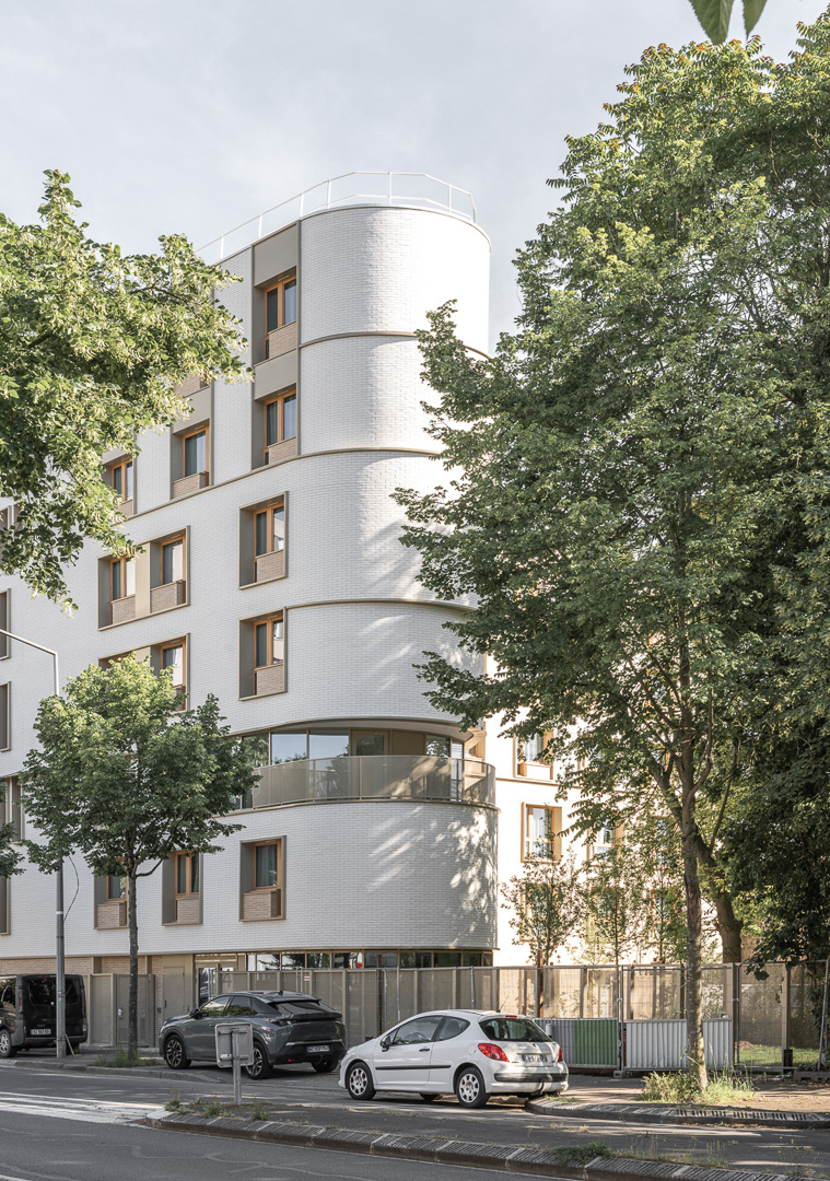 Bâtiment élégant en angle tout en arrondis, en plaquette blanche courbée, larges fenêtres en bois et végétation